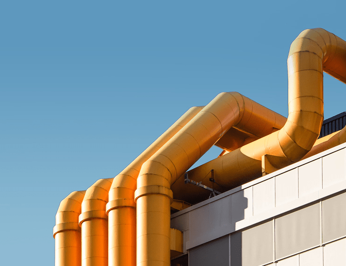 Желтые трубы на крыше здания под голубым небом